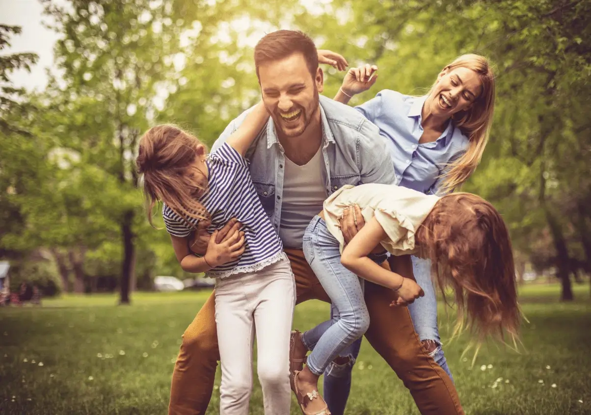 Fotografia de uma família sorrindo em uma área verde